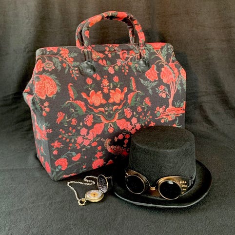 A carpet bag, fob watch, top hat and goggles 